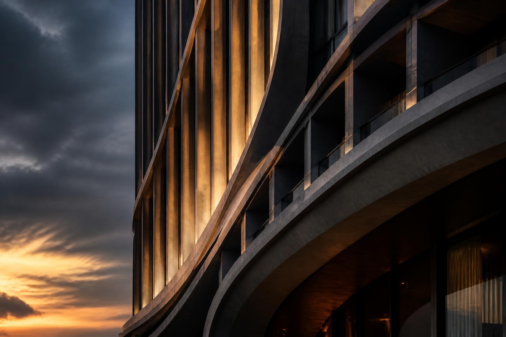 Curved concrete facade of a WW Infra tower at dusk